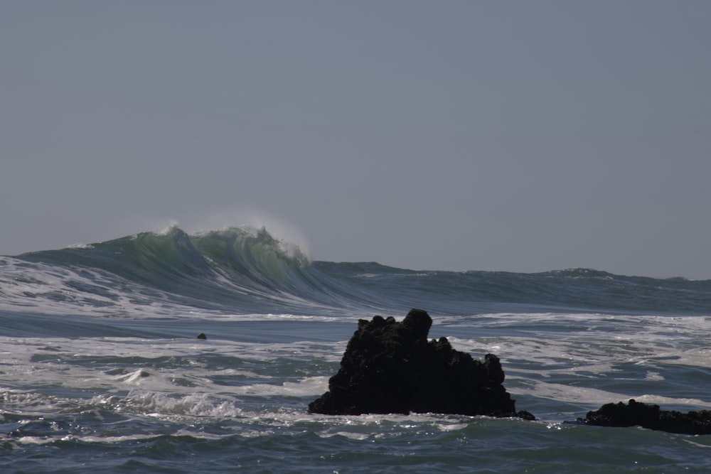 a large wave is crashing over a rock in the ocean