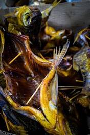 Multiple smoked fish with visible skewers used to hold the fish open, displaying their detailed textures and golden-brown coloration. The fish are arranged closely together, creating a visually dense pattern with overlapping fins and tails.