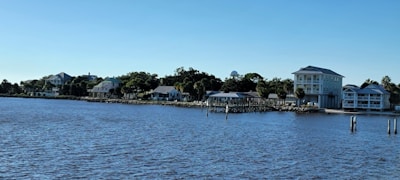 A beautiful waterfront home with a dock and boats on a calm sunny day.