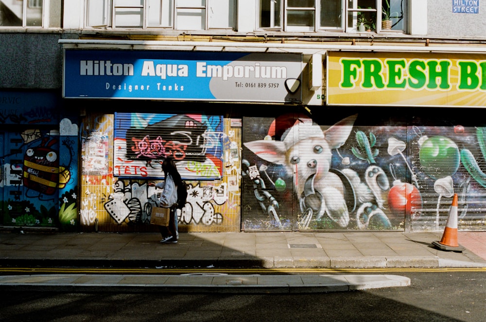 a woman walking down a street past a store front