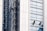 Several workers are suspended on the side of a modern skyscraper, engaged in cleaning the windows. They are equipped with safety harnesses and ropes, operating from different heights along the building's facade. The building's surface features reflective glass panels that capture the surrounding environment.