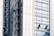 Several workers are suspended on the side of a modern skyscraper, engaged in cleaning the windows. They are equipped with safety harnesses and ropes, operating from different heights along the building's facade. The building's surface features reflective glass panels that capture the surrounding environment.