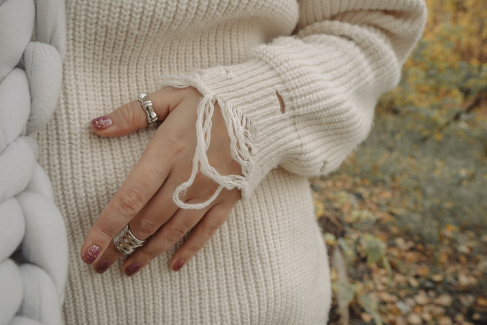 a woman in a white sweater holding onto a pile of pillows