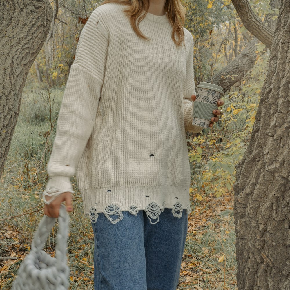 a woman standing in a forest holding a purse