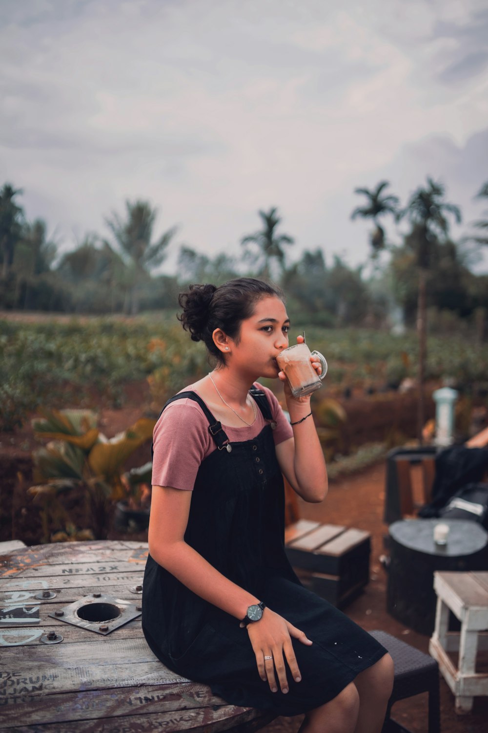 a woman sitting on a bench drinking from a cup