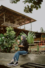 A serene woman in a sage green hijab sitting peacefully with a journal and cup of tea.