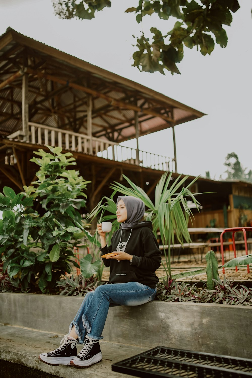 a person sitting on a ledge with a cup of coffee