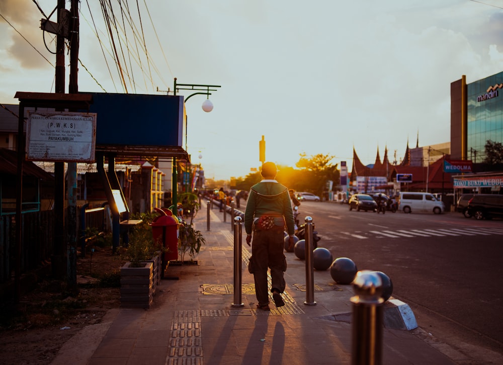 a man walking down a sidewalk next to a street