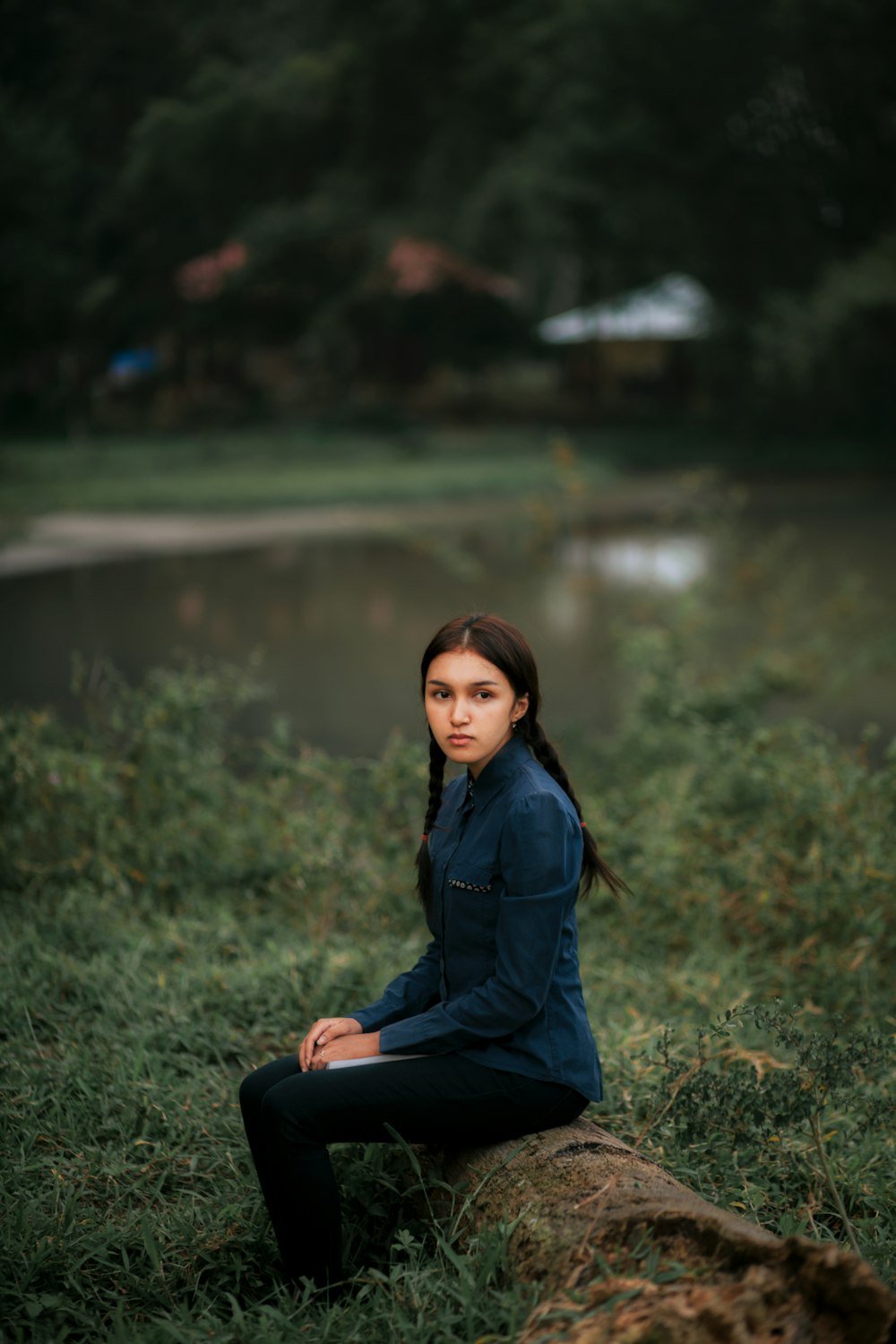 a woman sitting on a log in a field