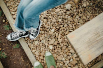 Close-up of a pair of well-worn walking shoes on a gravel path.
