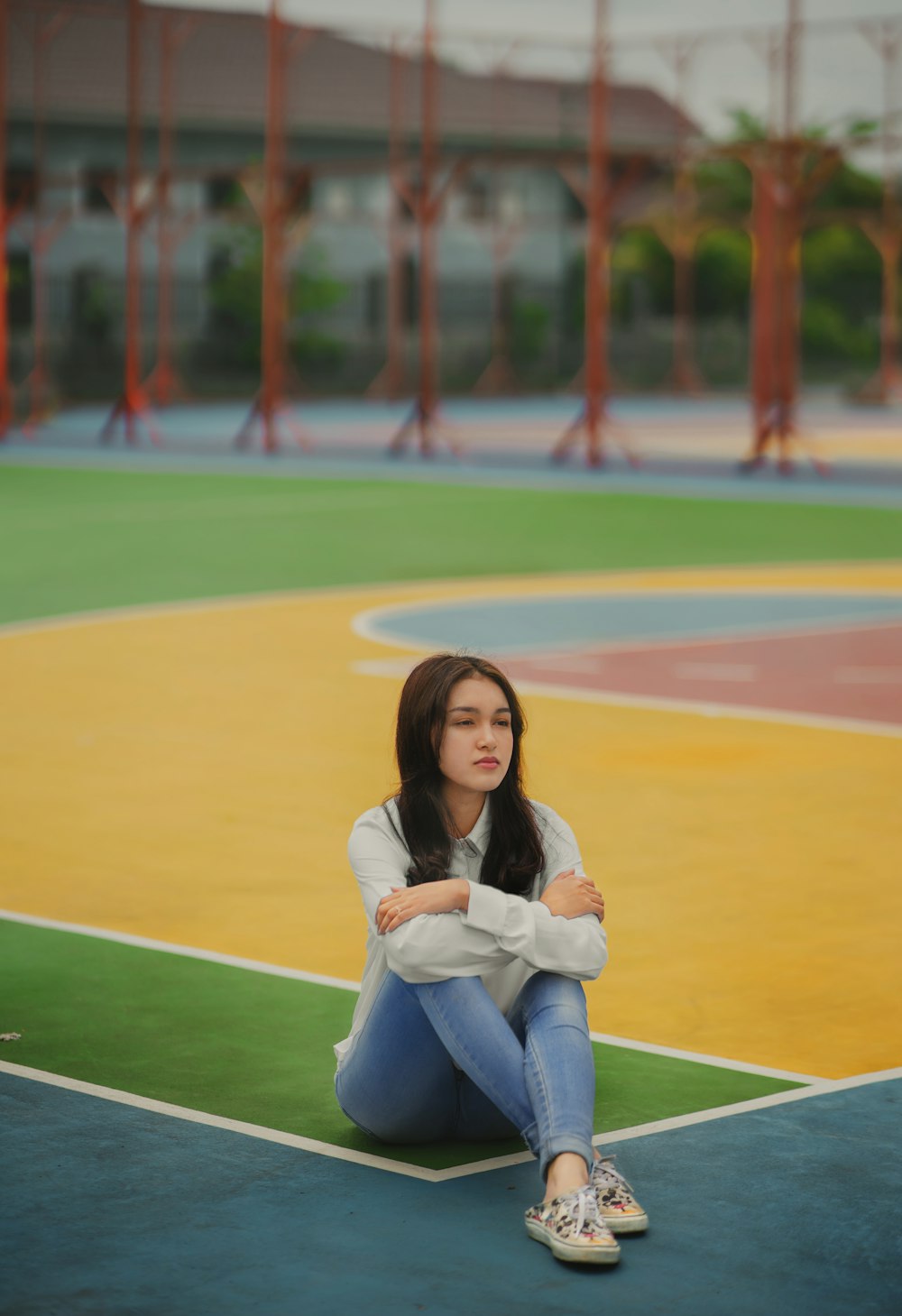 a woman sitting on a basketball court with her arms crossed