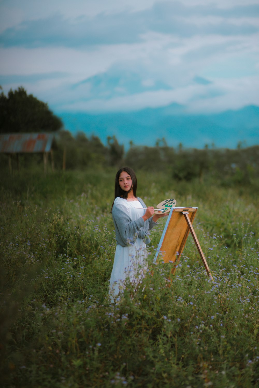 a woman standing in a field with a easel