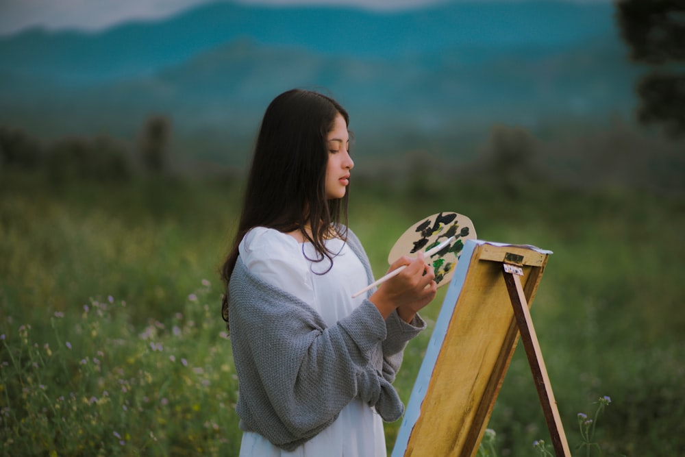 una mujer pintando un cuadro en un campo