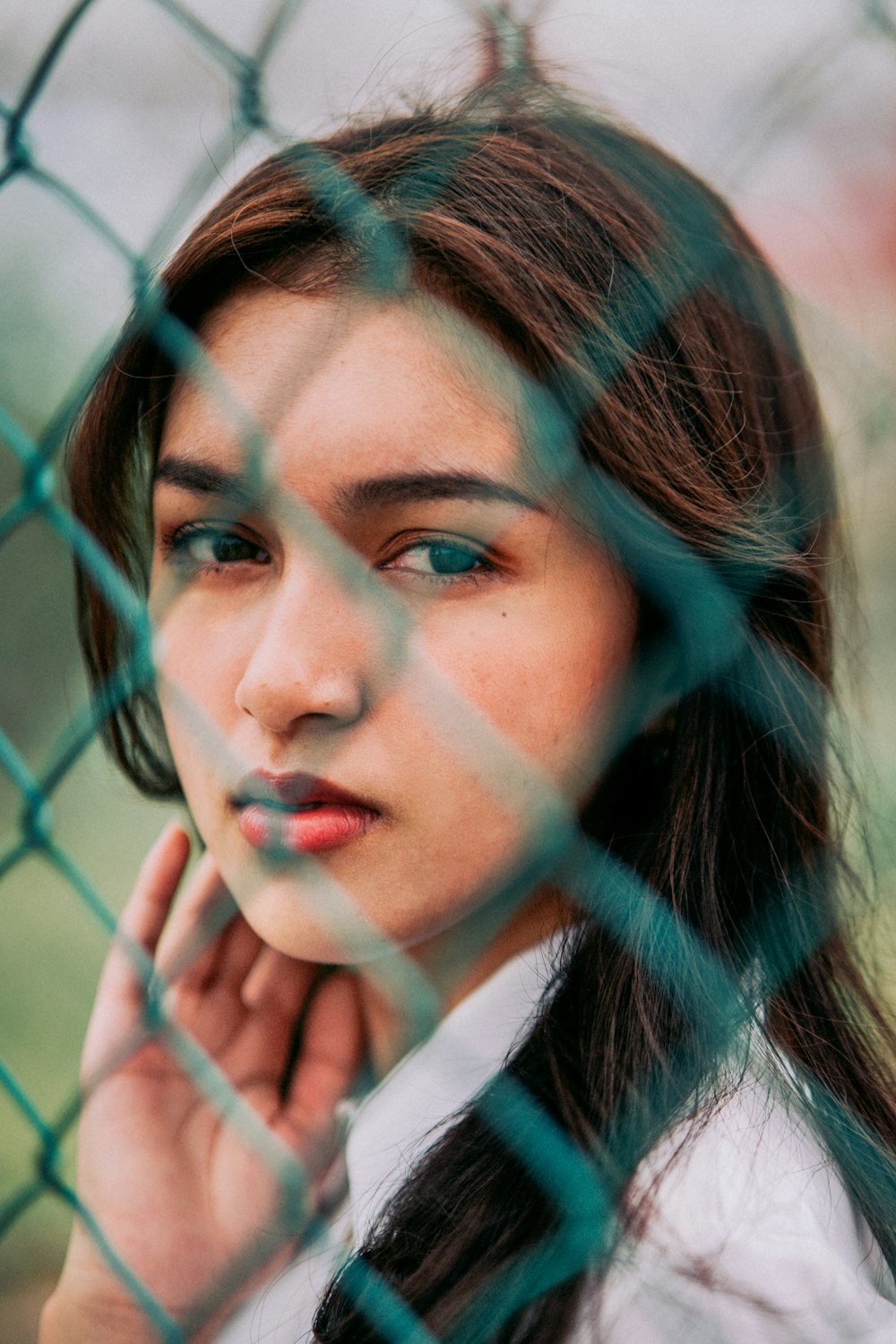 a woman standing behind a chain link fence