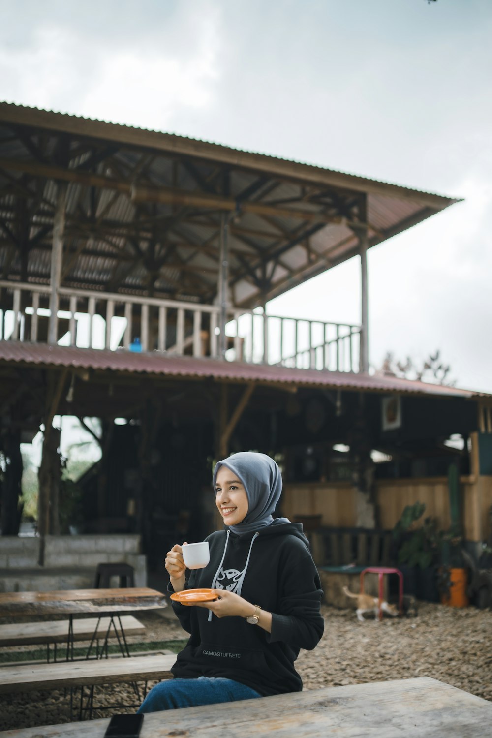 a woman sitting at a picnic table holding a cup of coffee