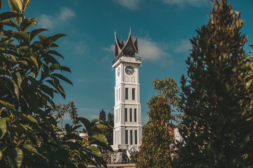 a tall white clock tower with a clock on each of it's sides