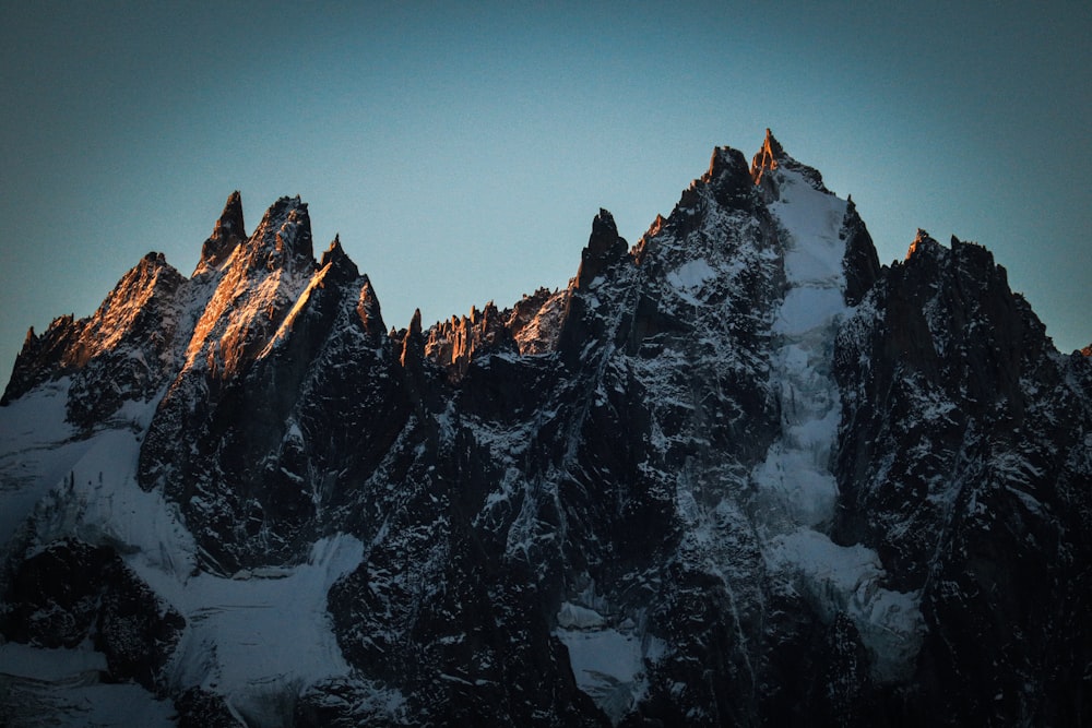 a very tall mountain covered in snow under a blue sky