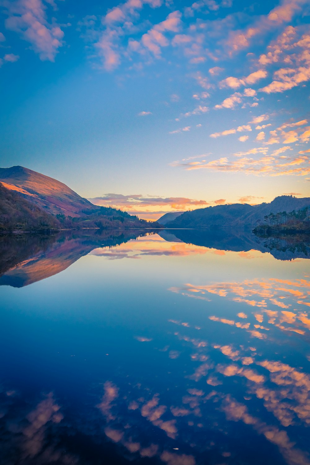 a lake surrounded by mountains under a blue sky