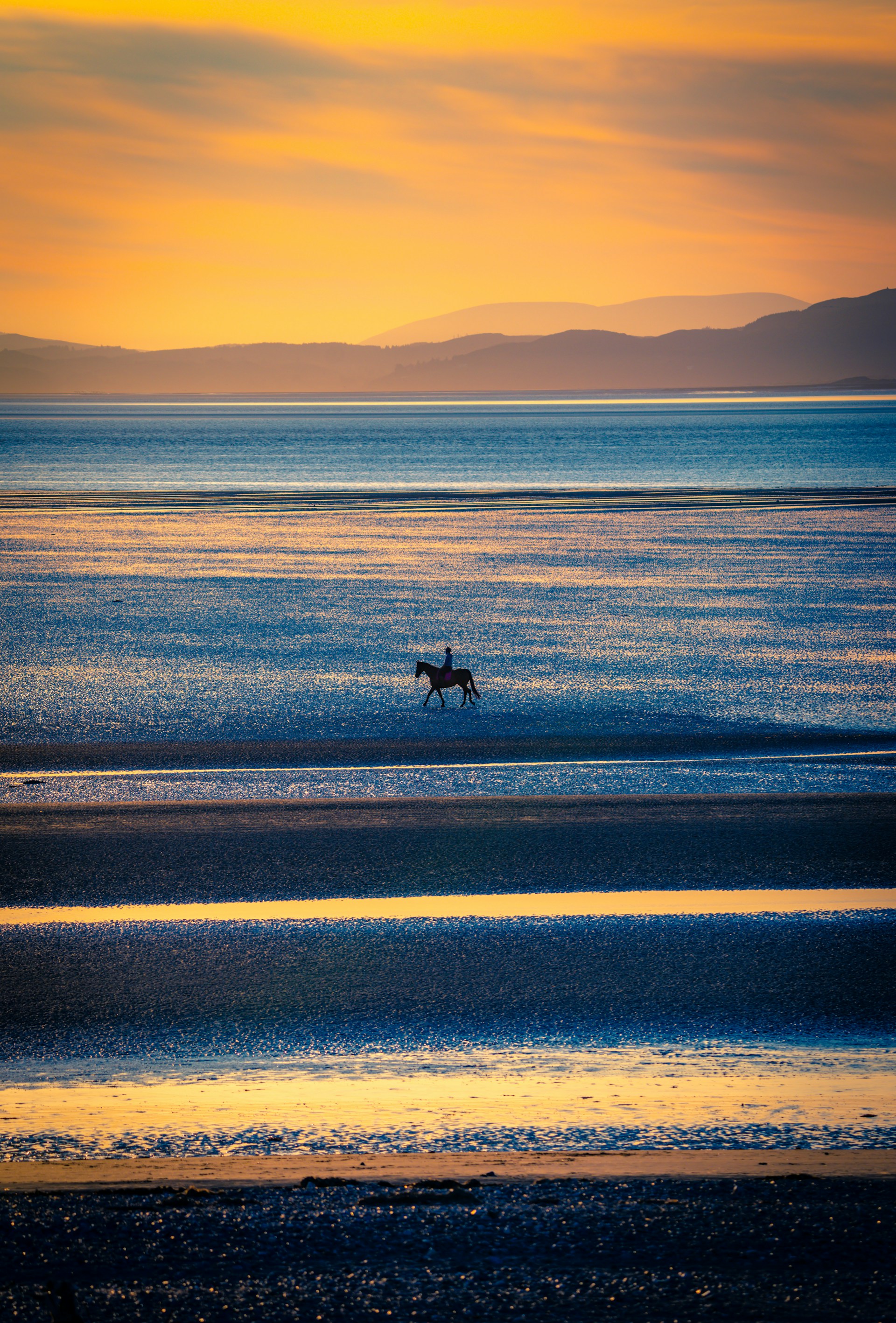 Sunset horseback ride along the golden sands of Playa Pitahaya with vibrant tropical skies.