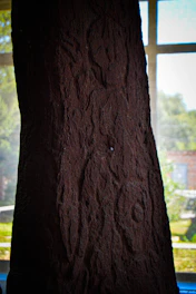 A towering broken stone monolith surrounded by mist and ancient glyphs, glowing faintly in low light.
