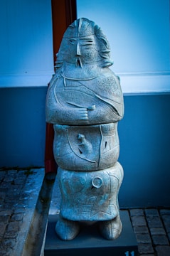 An elegant amazonite sculpture inspired by Andean motifs, displayed on a wooden pedestal.