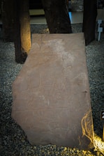 Ancient stone tablet with intricate carvings of mythological figures under soft, warm lighting.
