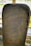 An ancient stone slab with inscribed runes carved into its surface. The stone has a rectangular shape with rounded edges and shows a dark, weathered texture. The inscriptions form a border around the stone, with some symbols appearing more worn than others.