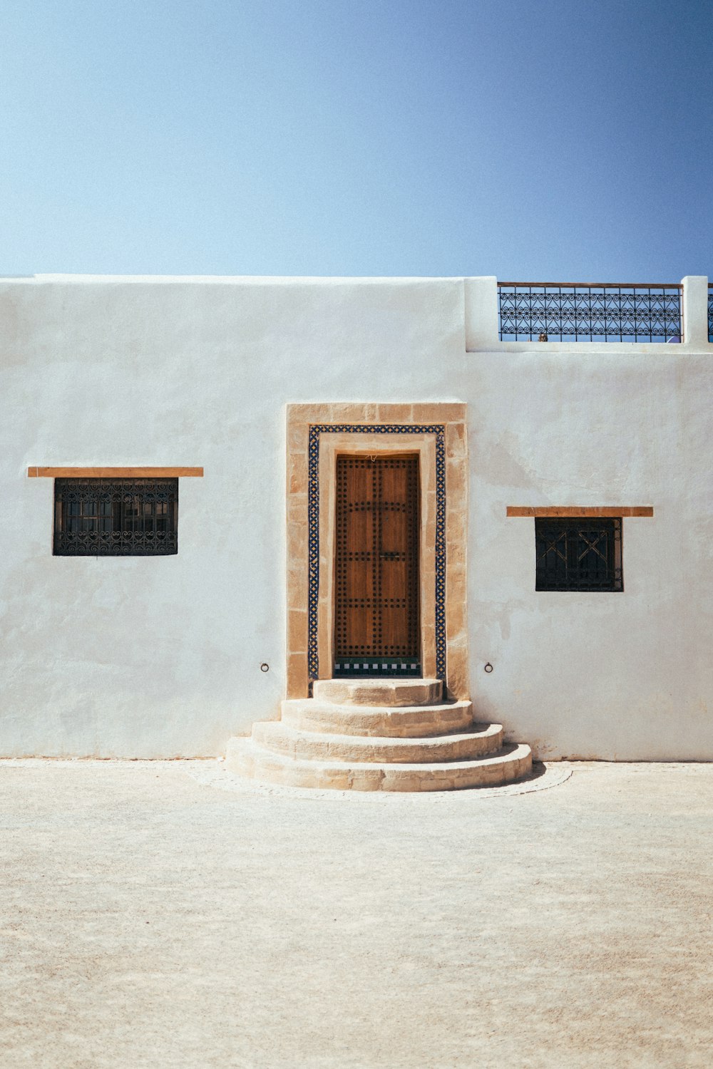 a white building with a brown door and steps