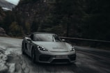 A sleek luxury sports car winding through a misty morning forest road.