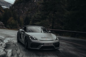 A sleek luxury sports car winding through a misty morning forest road.