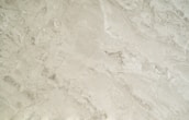 A close-up view of a smooth, creamy beige marble surface featuring intricate patterns and natural veining that give it a luxurious appearance.