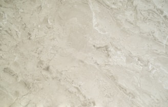 A close-up view of a smooth, creamy beige marble surface featuring intricate patterns and natural veining that give it a luxurious appearance.