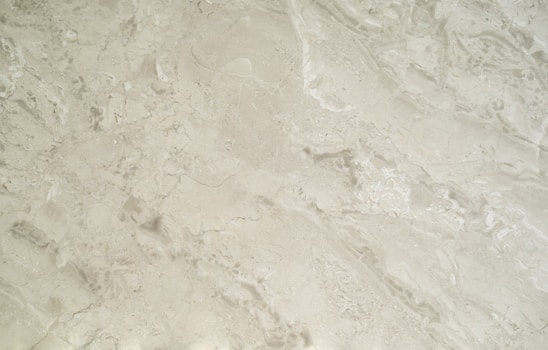 A close-up view of a smooth, creamy beige marble surface featuring intricate patterns and natural veining that give it a luxurious appearance.