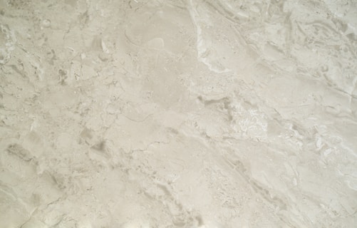 A close-up view of a smooth, creamy beige marble surface featuring intricate patterns and natural veining that give it a luxurious appearance.