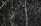 A dark marble surface characterized by intricate white veining and scattered white specks. The texture appears smooth and polished, common in natural stone countertops or flooring.