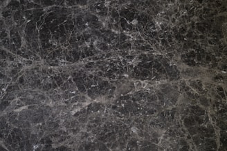 Minimalist black marble texture with subtle platinum highlights evoking precision and stability.