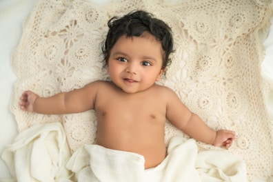 A happy baby playing on a soft blanket.