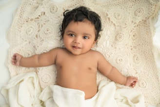 A happy baby playing on a soft blanket.