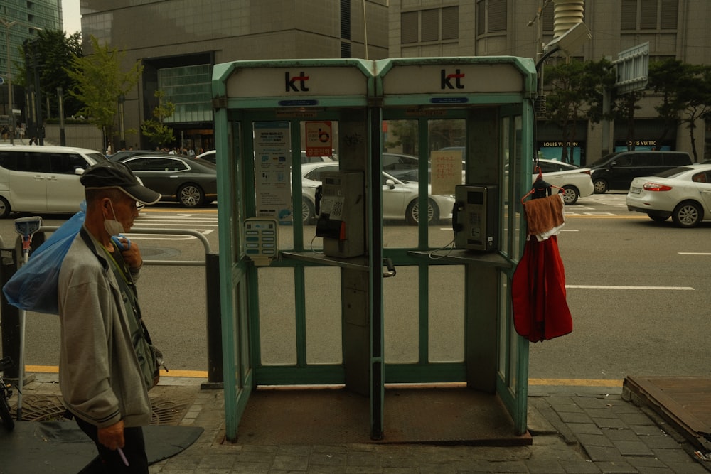 a man standing next to a public phone booth