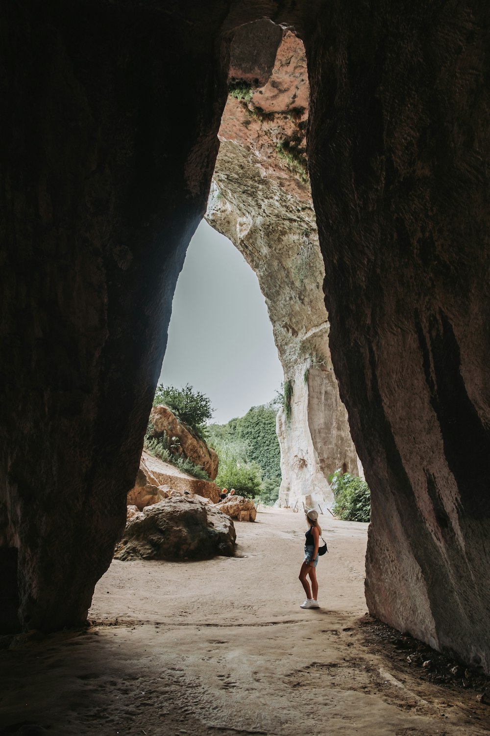 a woman standing in a cave between two large rocks
