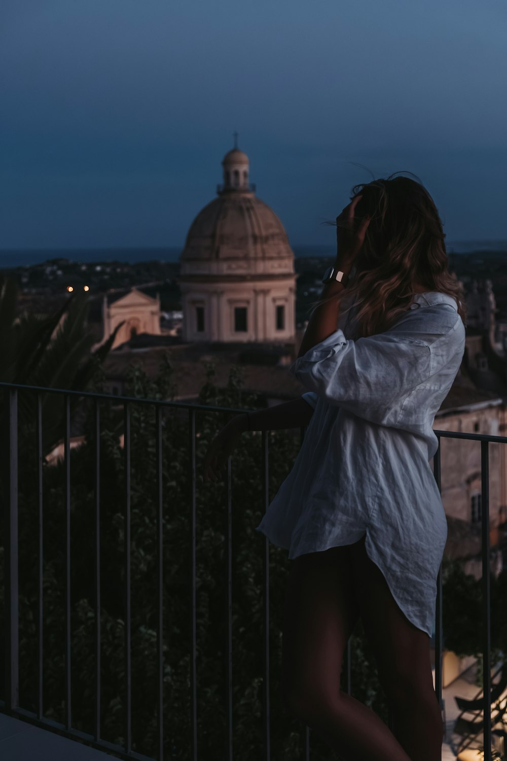 a woman standing on top of a balcony talking on a cell phone