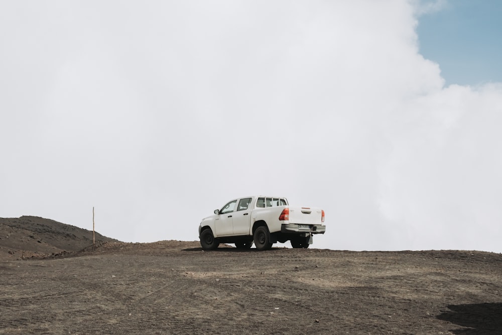 a white truck parked on top of a dirt hill