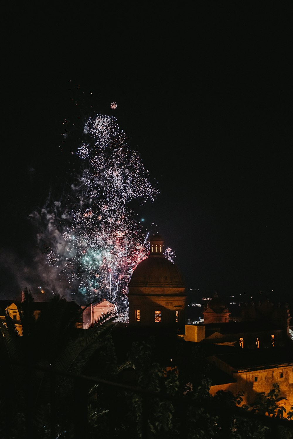 fireworks are lit up the night sky over a city