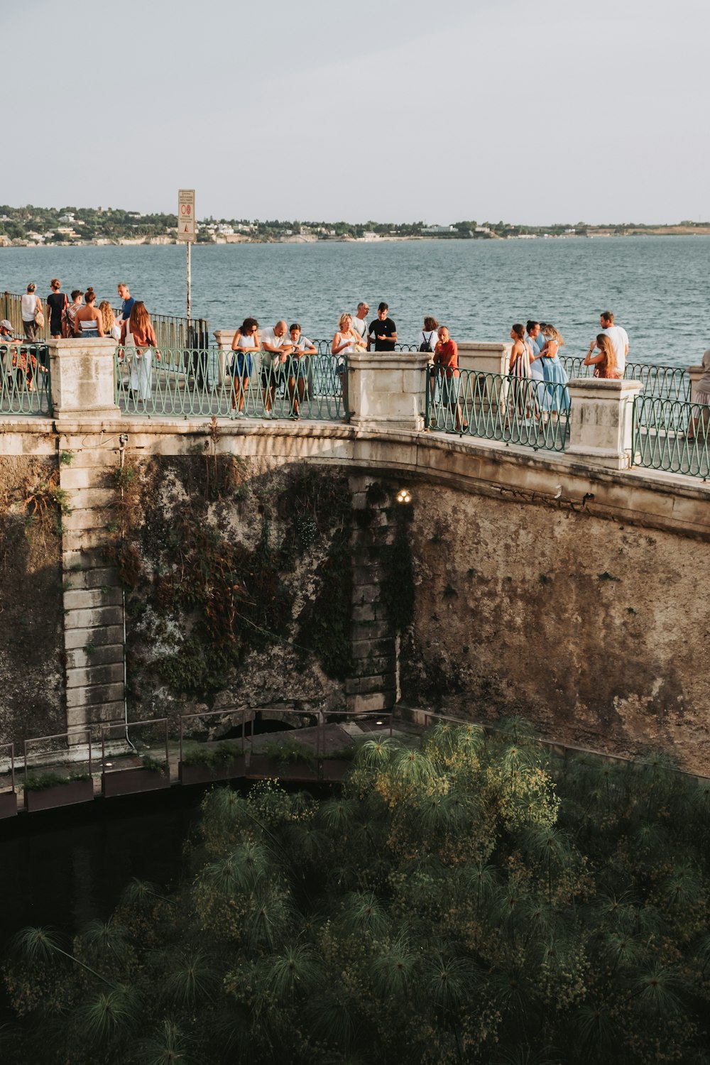 a group of people standing on a bridge next to a body of water