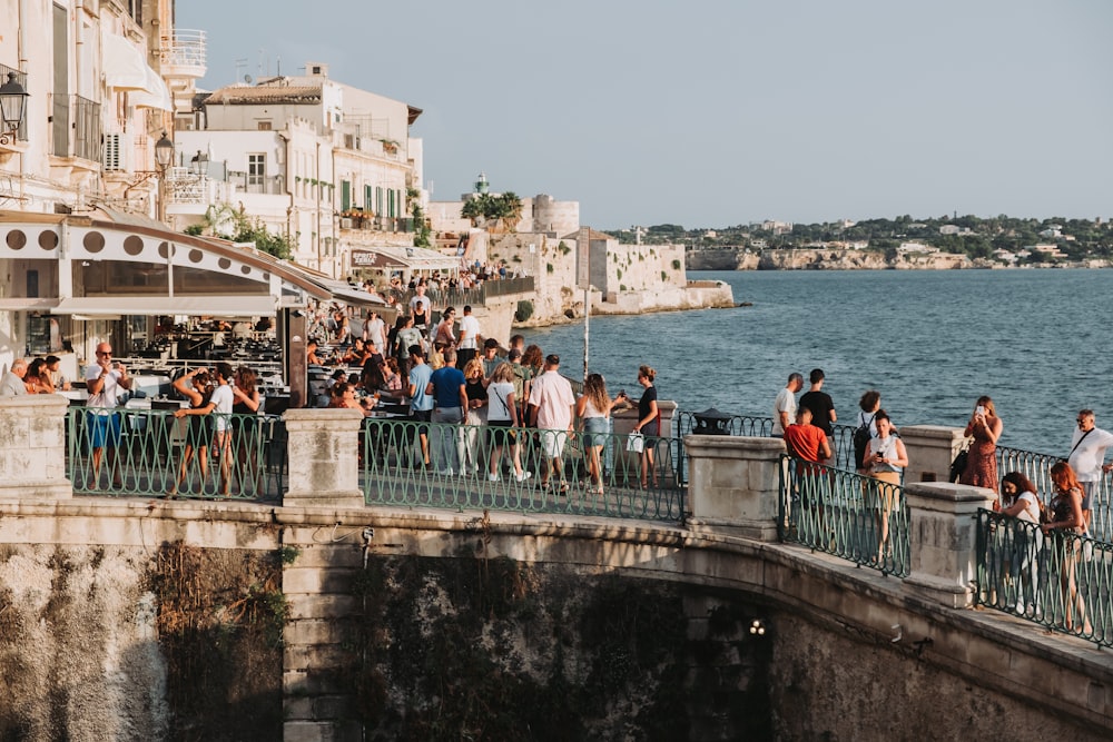 Un grupo de personas de pie en un puente junto a un cuerpo de agua