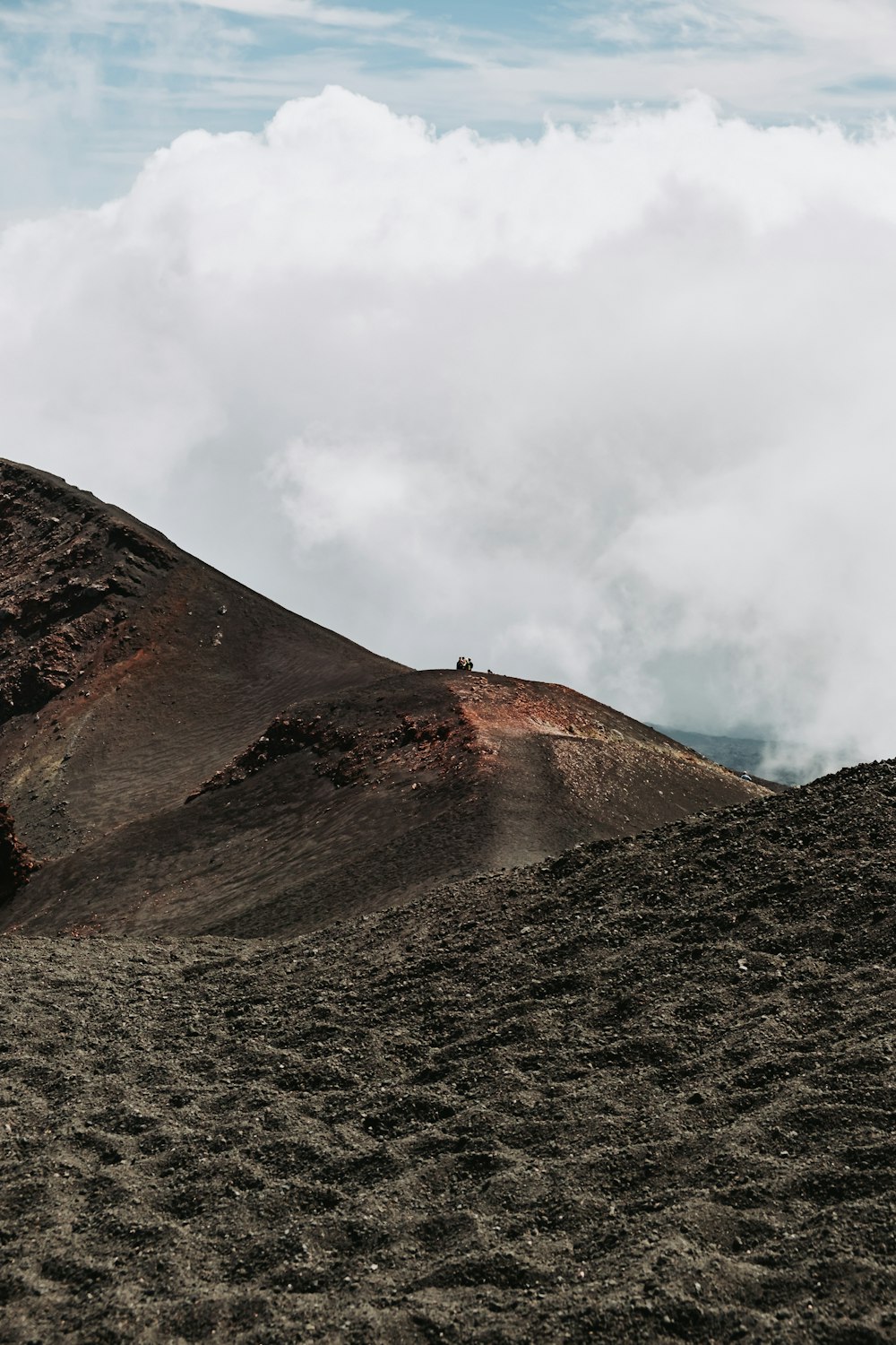 a hill covered in dirt with clouds in the background