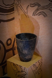 Close-up of a ceramic vase with intricate leaf patterns and subtle cracks resembling ancient bark.