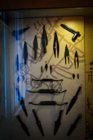 A collection of throwing axes with polished wooden handles displayed on a leather mat.