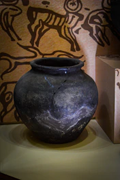 A weathered clay pot with ancient symbols painted in faded colors.