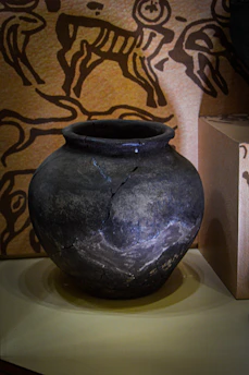 A weathered clay pot with ancient symbols painted in faded colors.